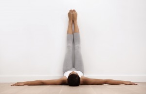 A young woman stretching against a wall before exercise